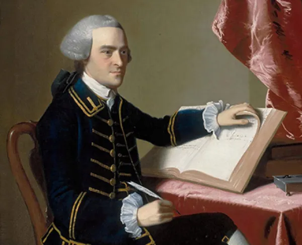 A portrait of a man wearing a grey wig and a blue coat with gold buttons sits at a table and looks to the distance. His left hand turns a page in an account or ledger book while his right hand holds a quill pen. 